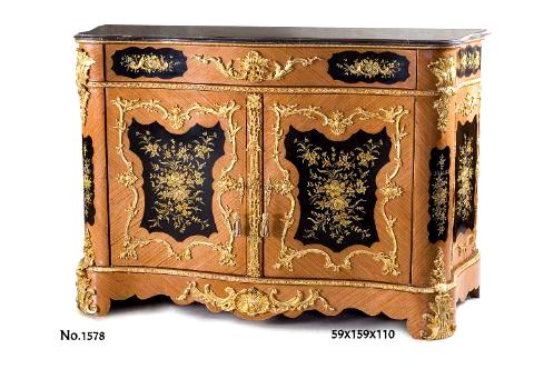Enchanting Napoleon III and Rococo style ormolu-mounted veneer inlaid and hand painted side cabinet, after the model Circa 1860, surmounted by a serpentine stepped black marble top above a large frieze drawer with double ormolu bands centered by foliate acanthus mount with foliate scrolles, flanked to each side by a floral painted panel with ormolu foliate handle, above a pair of cupboard doors, each with ormolu keyhole escutcheon and centered by a black background cartouche with spring flowers within a C scrolled and foliate frame with cabuchon, the interior fitted with an adjustable shelf, separated with a very fine chiseled pierced strapwork, the sides each with conforming panels hand painted as well with flowers with a matching ormolu frame of the same work, the scalloped apron centered by a large central ormolu shell issuing C Rococo works, on shaped feet with foliate clasps